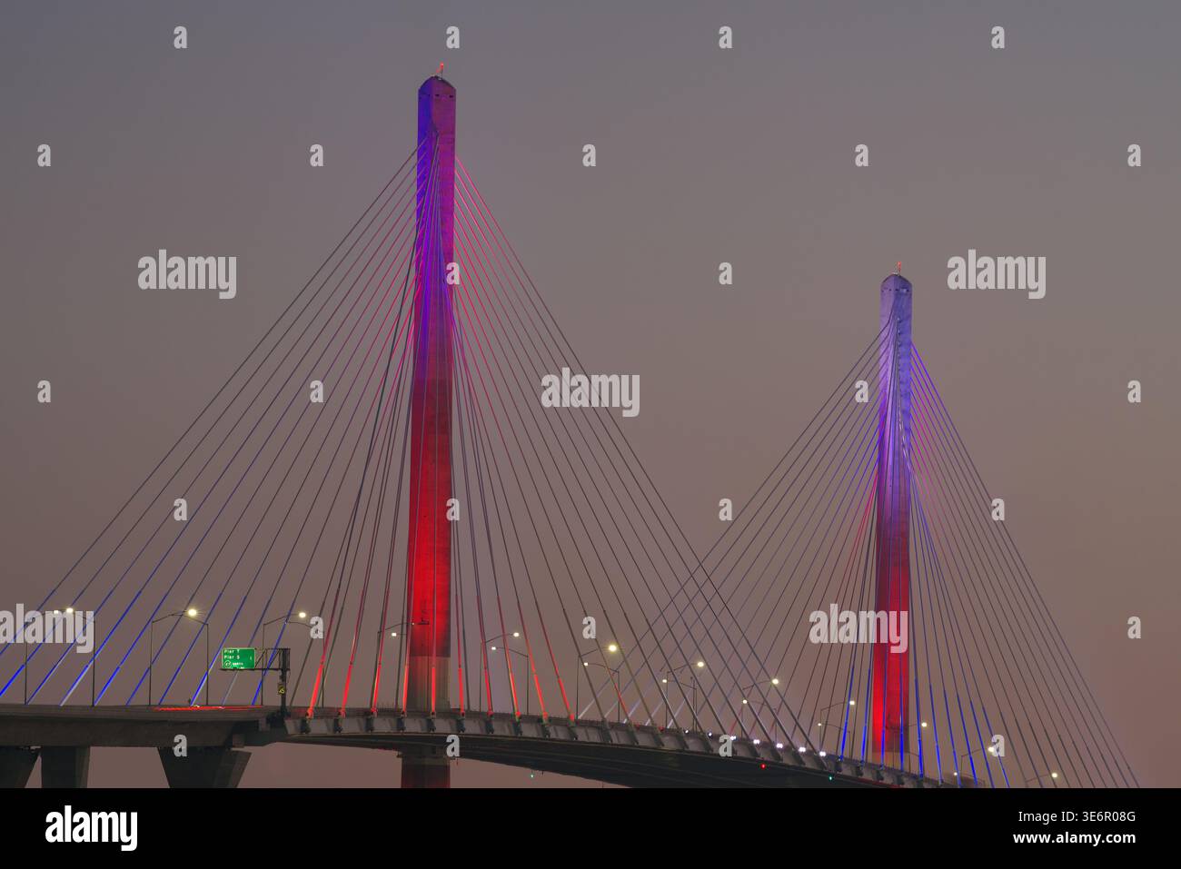 Il Long Beach International Gateway Bridge, in stile Cable-Stay, è illuminato in rosso e blu al crepuscolo. Foto Stock
