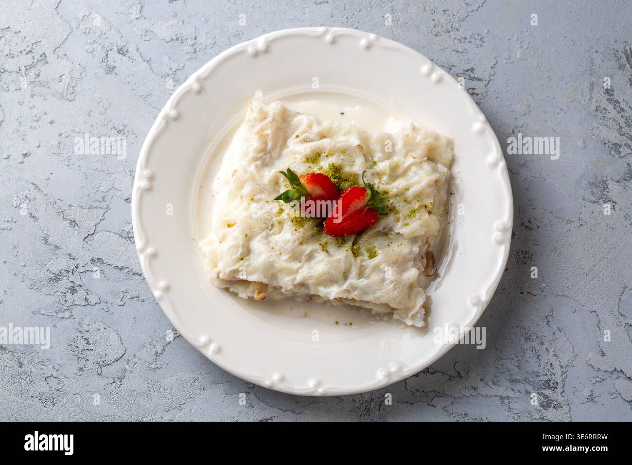 Tradizionale dessert turco di Gullac con fragole di latte e pistacchi serviti su un piatto Foto Stock