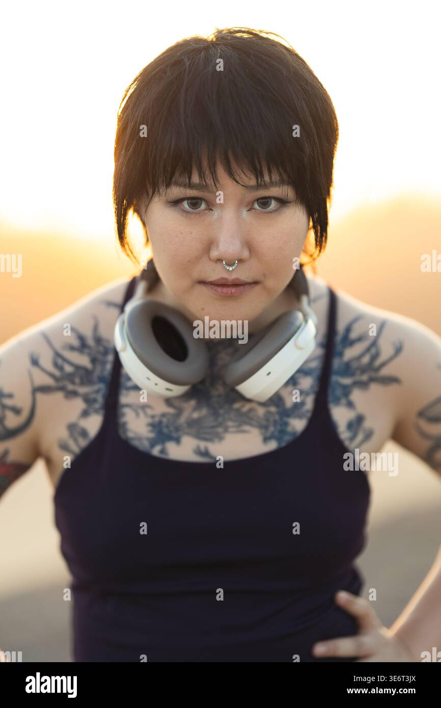 Giovane donna tatuata sicura di sé che guarda la macchina fotografica Foto Stock