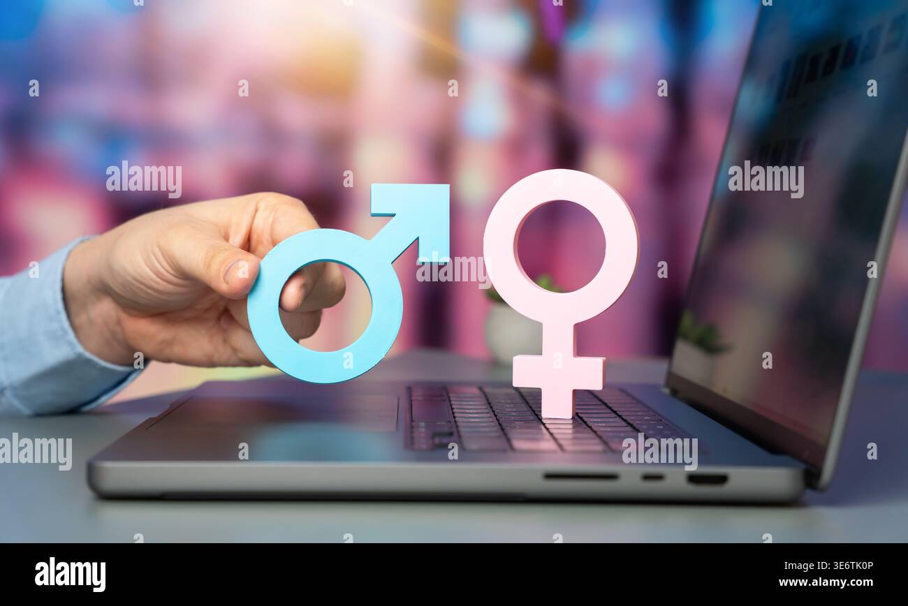L'uomo tiene i simboli di genere maschile e femminile sulla tastiera di un notebook. Concetto di incontri online, ricerca di un partner, incontro di persone su Internet e r Foto Stock