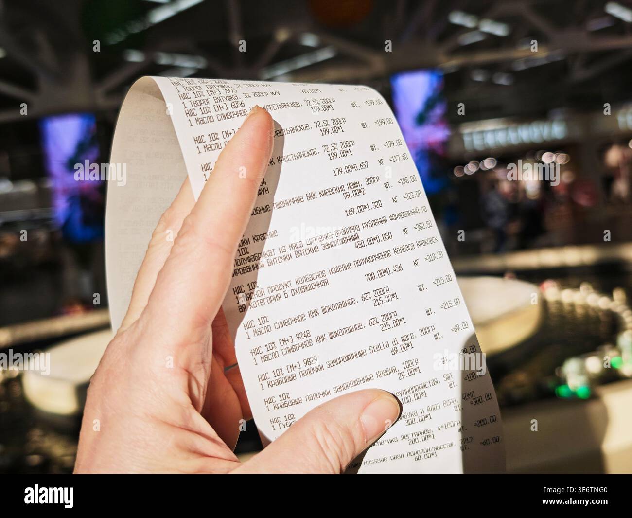Kirov, Russia - 8 febbraio 2026: Una mano tiene una lunga ricevuta del negozio dopo lo shopping. La ricevuta elenca gli articoli acquistati e i dettagli di pagamento. L'impostazione A. Foto Stock