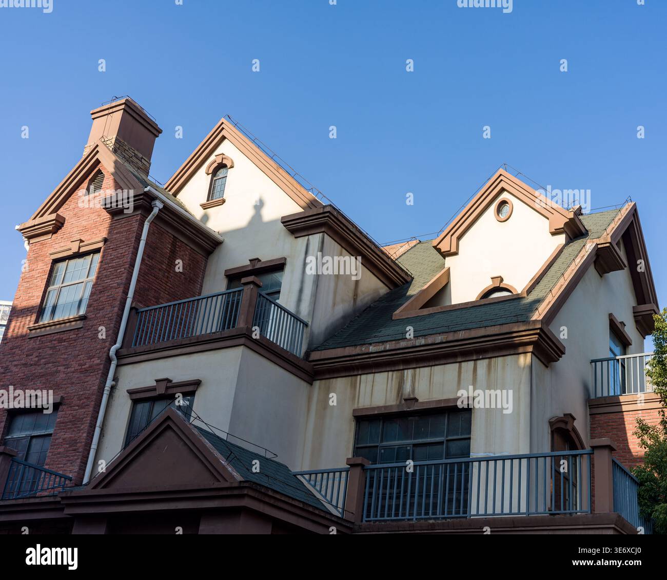 Vista ad angolo basso di un edificio esterno in stile europeo classico caratterizzato da molti frontoni, finestre dormitori e una combinazione di pareti in mattoni e stucco Foto Stock
