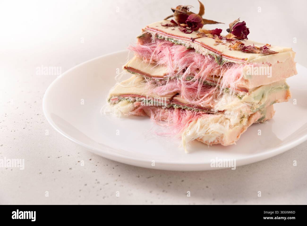 Dessert artistico a strati con un'ariosa texture di caramelle di cotone e petali di rosa. Concetto di dolci premium, design alimentare moderno, estetica di bellezza e din raffinato Foto Stock