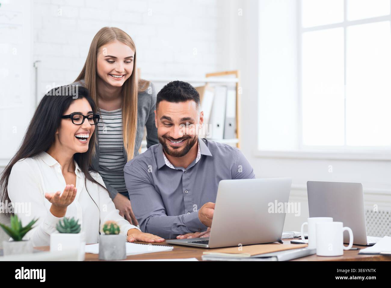 Tre dipendenti entusiasti ricevono buone notizie sul notebook Foto Stock