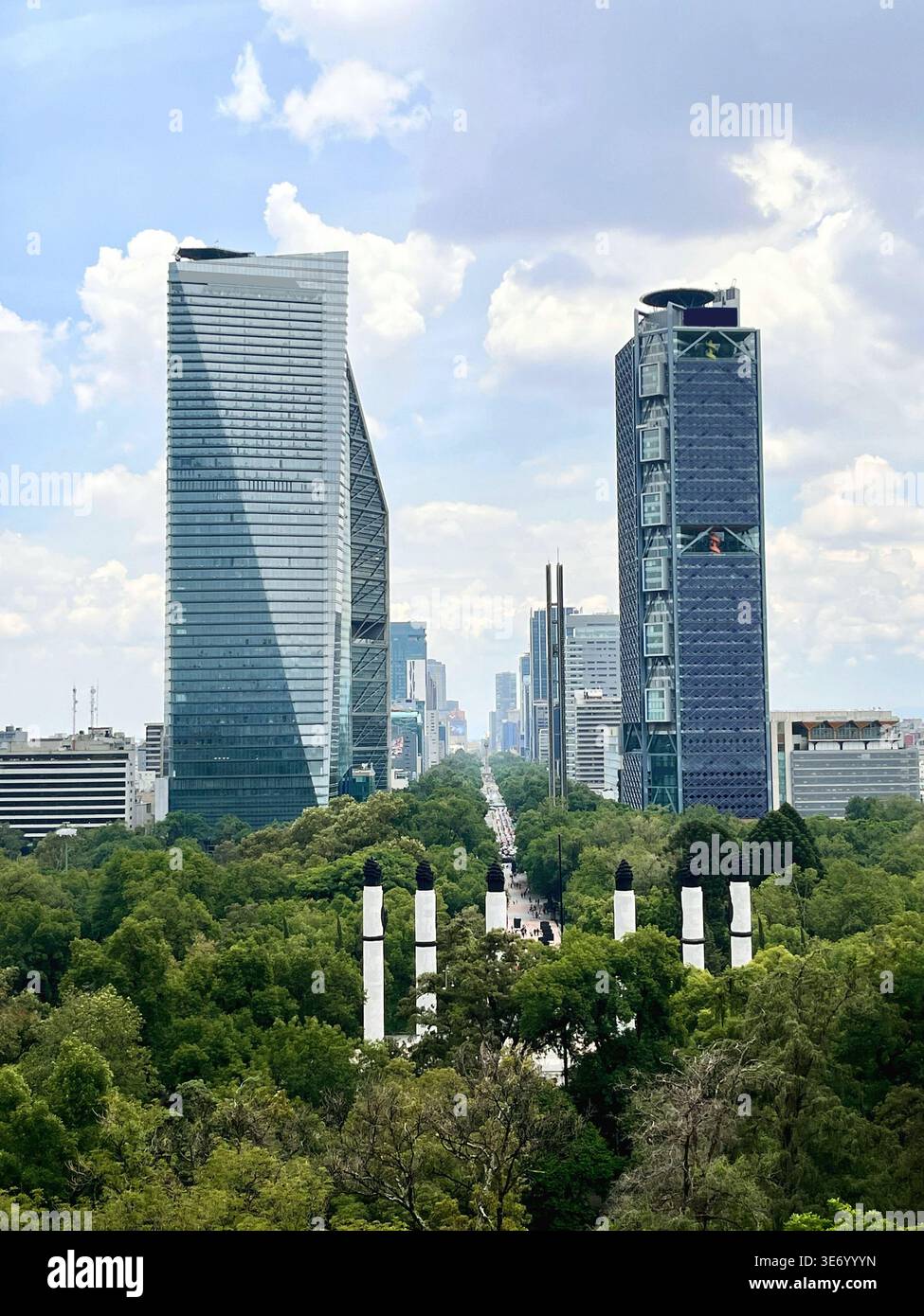 Vista aerea urbana che mostra i grattacieli aziendali del Paseo de la Reforma che emergono sopra la fitta vegetazione della foresta di Chapultepec sotto un cielo nuvoloso - Immagine stock catturata con smartphone
