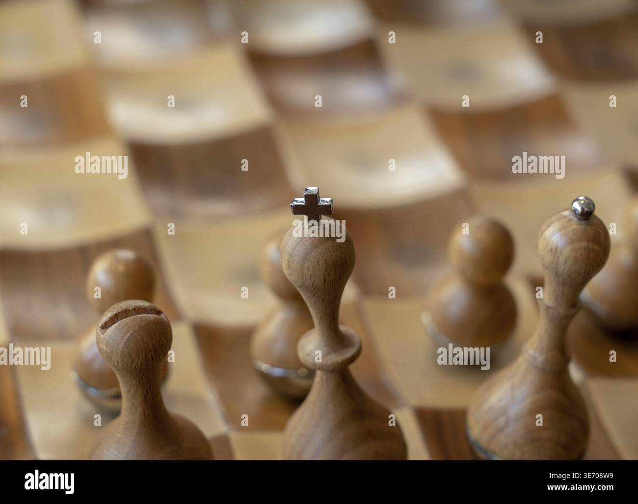 Focalizza l'attenzione sulla croce sulla parte superiore del set di scacchi con pezzi di legno intagliati Foto Stock