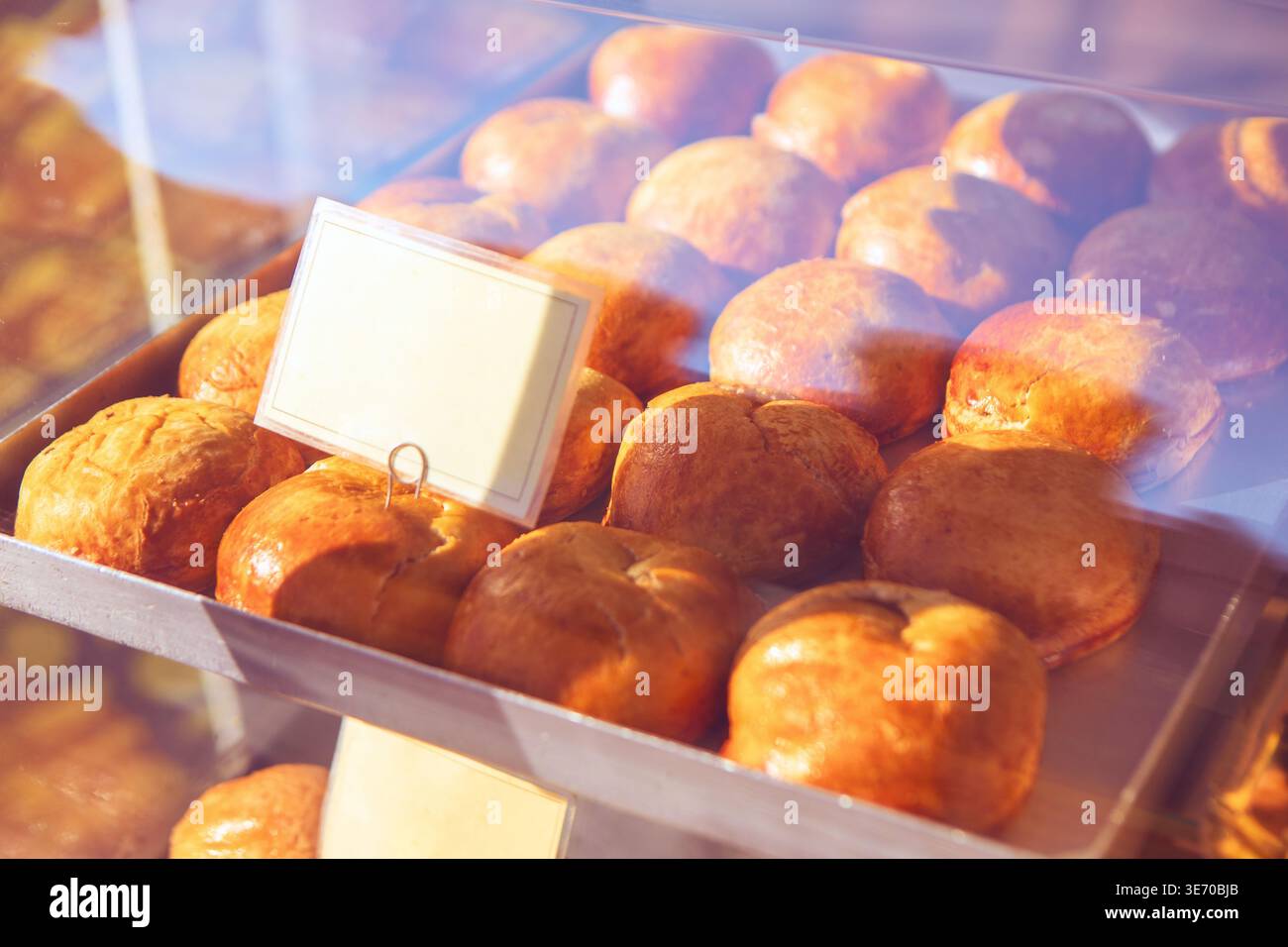 I panini appena sfornati sono esposti in una cassa da forno, che si illuminano al caldo sotto la luce del sole. La scheda etichetta vuota ti aspetta un nome o un prezzo per questo delizioso passato Foto Stock