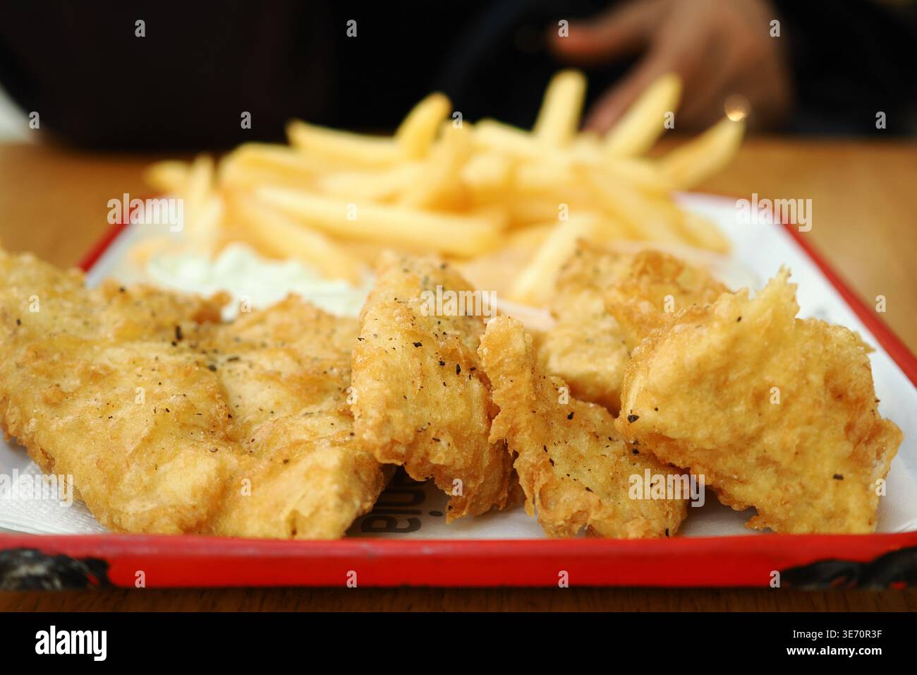 Pesce fresco e patatine fritte servite su un vassoio presso un ristorante Foto Stock