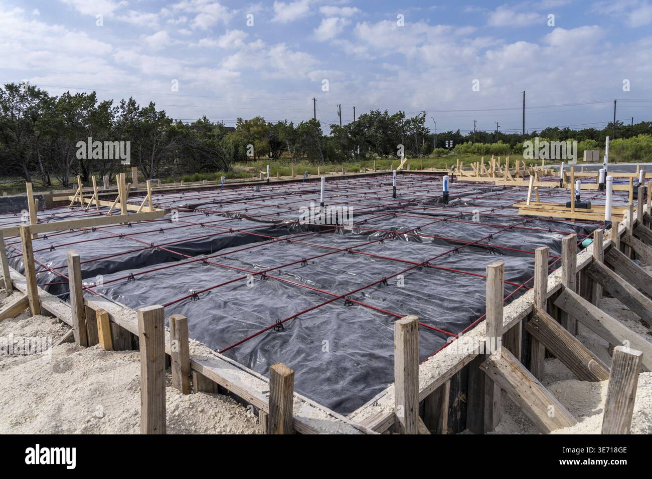 Trincee nella sabbia per tubazioni idrauliche e di scarico con acciaio impermeabile e rinforzante per la base della soletta di fondazione Foto Stock