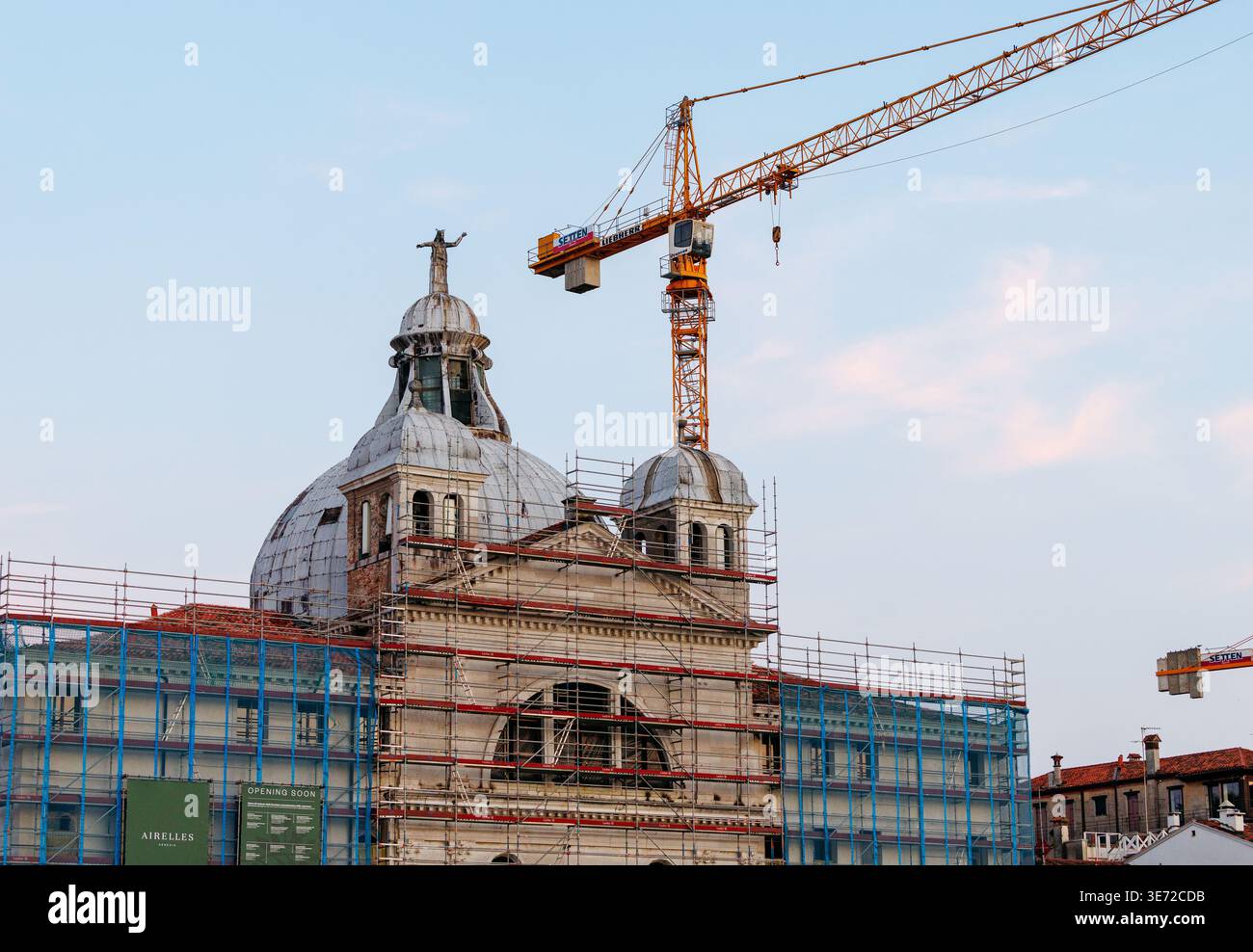 Venezia, Italia - 23 giugno 2025: Il cantiere presenta un edificio storico in fase di restauro con ponteggi e gru, mettendo in risalto lo sviluppo urbano Foto Stock