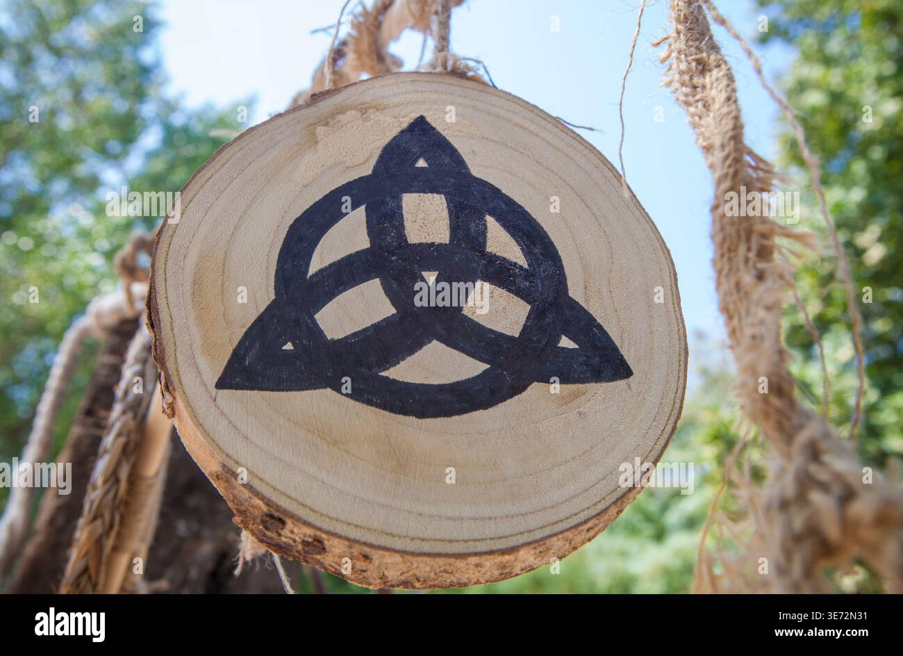 Simbolo di Triquetra dipinto sulla fetta di tronco dell'albero. Ricostruzione del campo militare celtico. Foto Stock