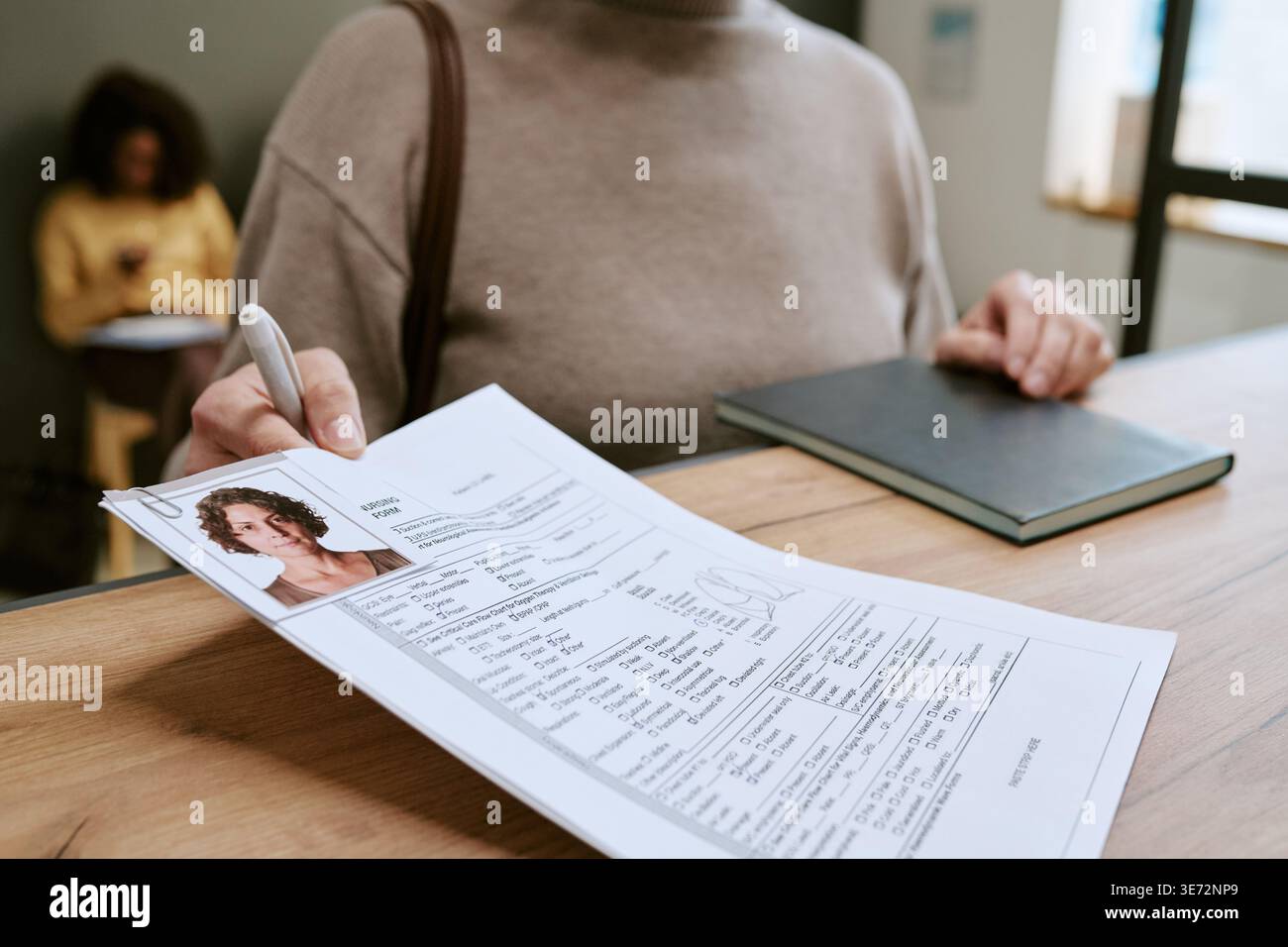 Donna di mezza età che presenta il modulo di richiesta alla reception Foto Stock