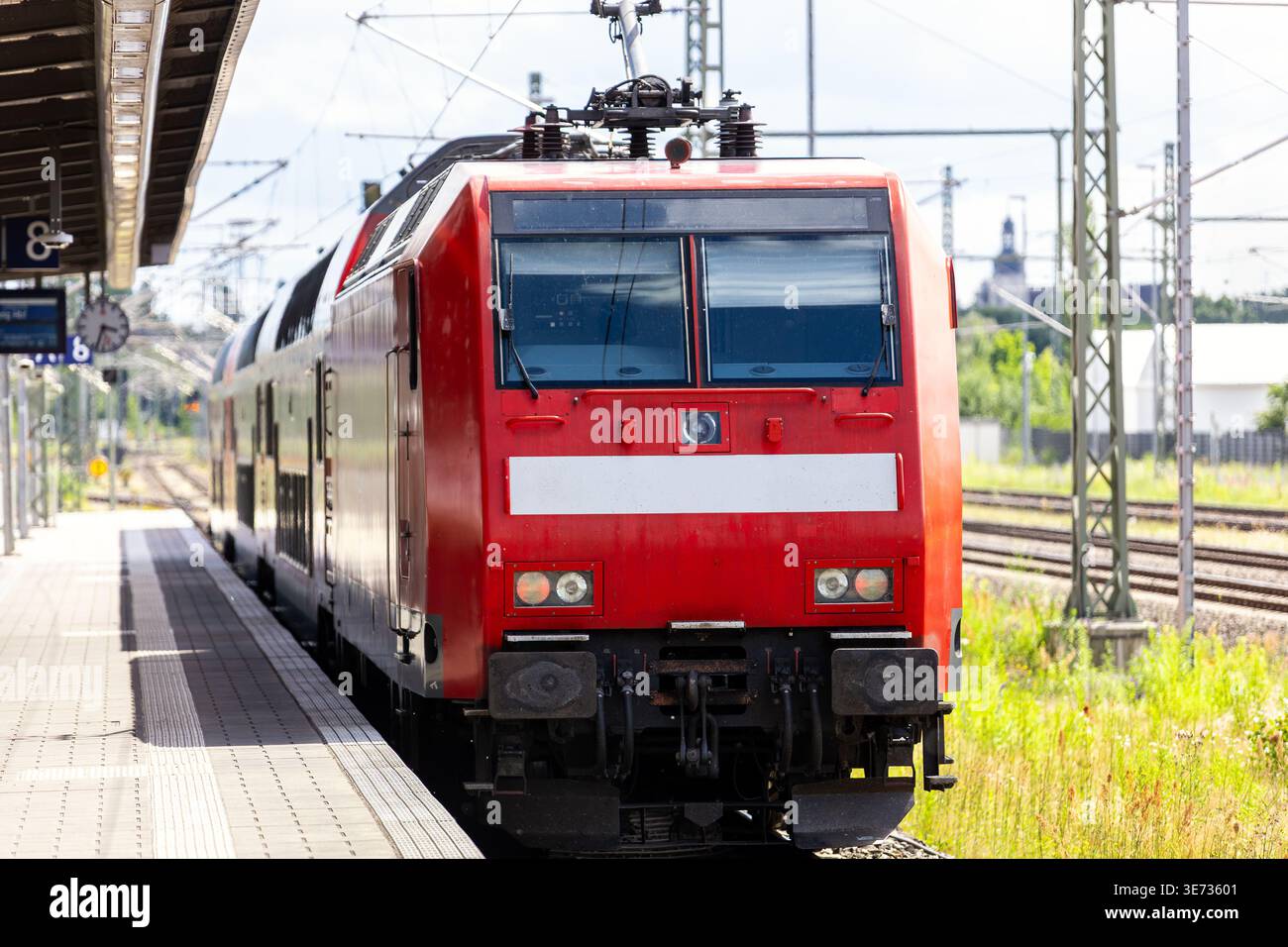 Stazione ferroviaria regionale rossa, banchina della locomotiva, stazione ferroviaria tedesca, binari di cavi catenari. Pendolare per l'infrastruttura del trasporto ferroviario di passeggeri Foto Stock