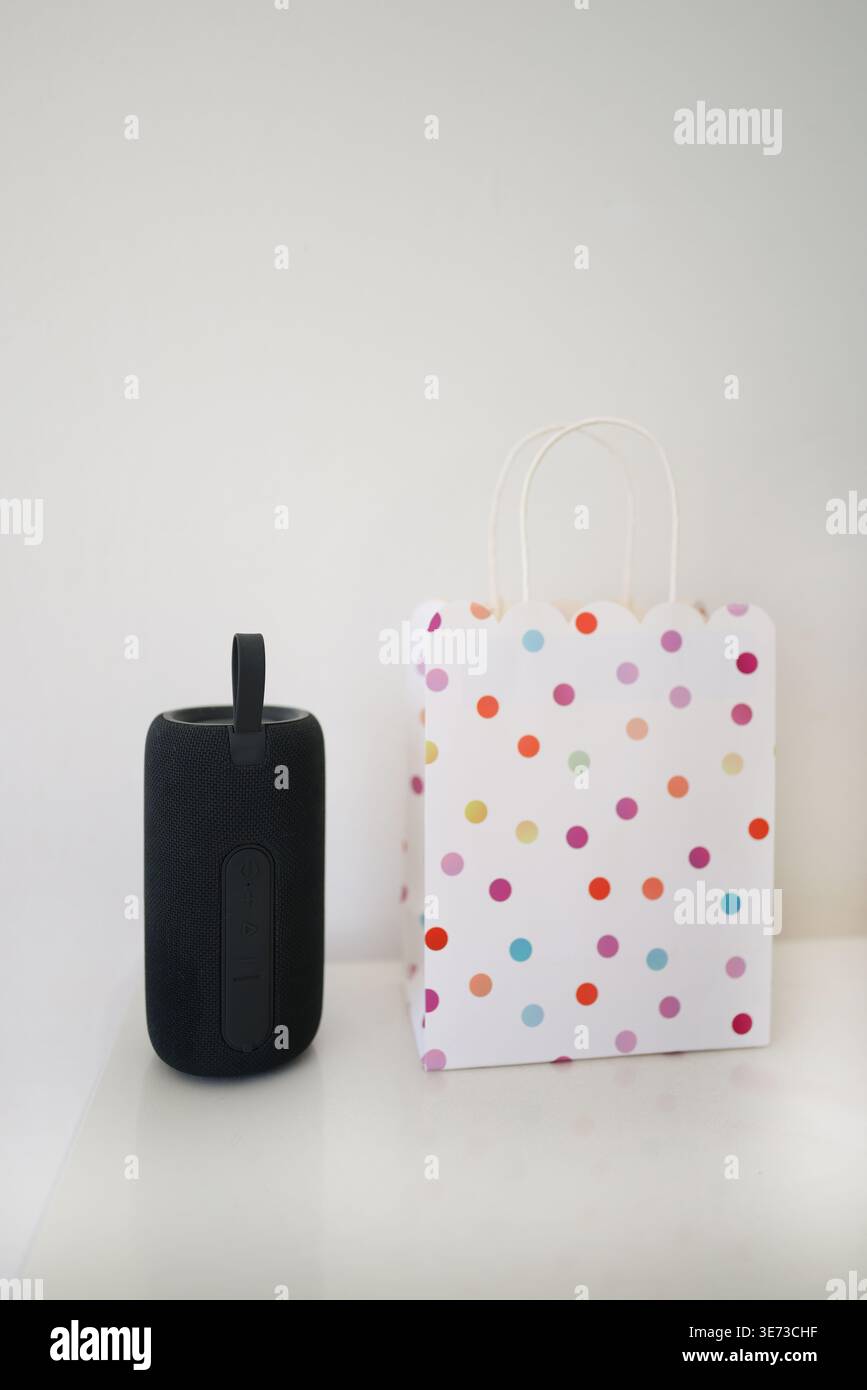 Altoparlante portatile accanto alla borsa regalo colorata su sfondo bianco, stile di vita moderno e concetto regalo. Foto Stock