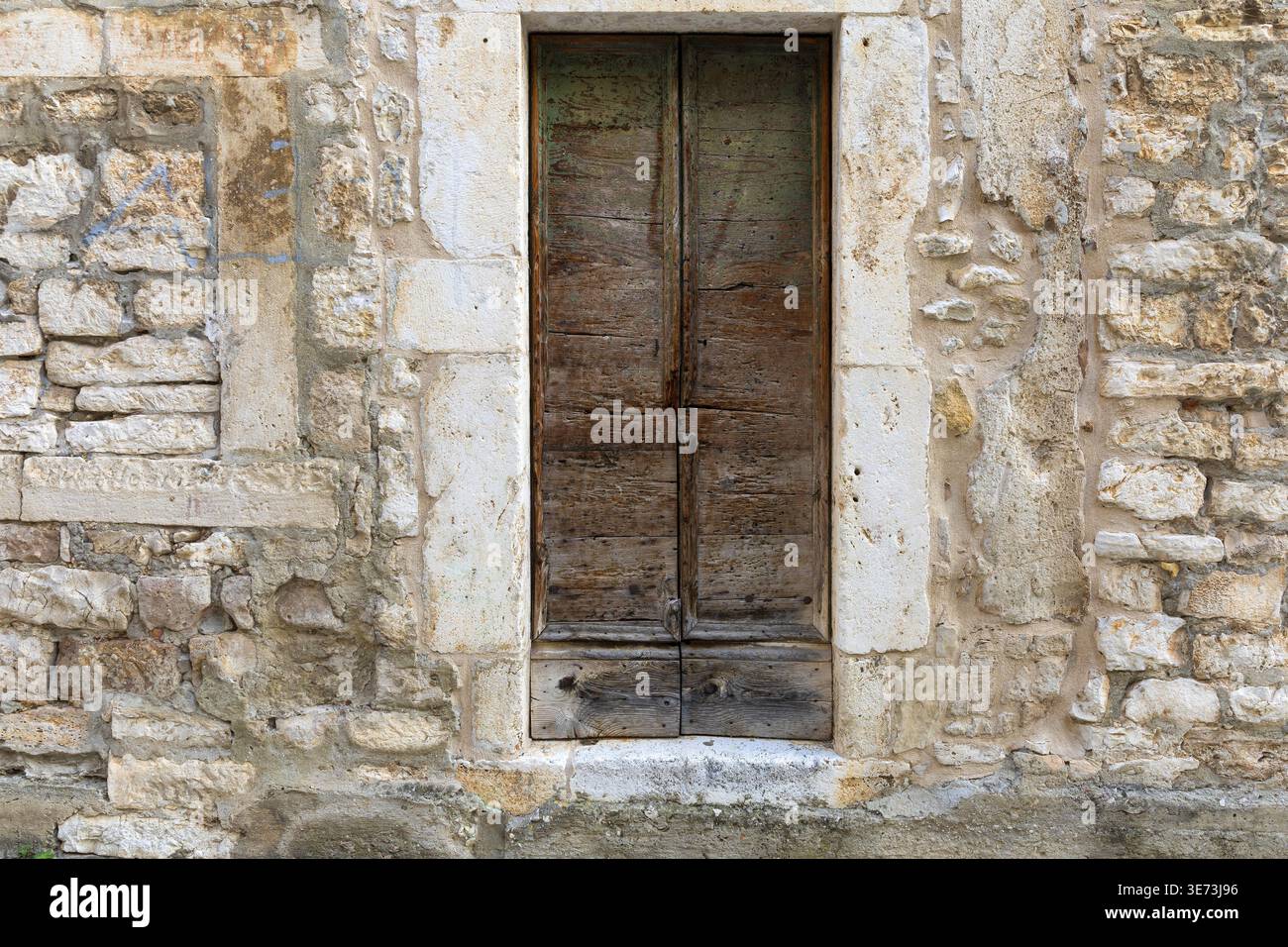 Porta in legno invecchiato con pareti in pietra intemprata. Dettagli architettonici rustici con texture naturali e carattere vintage. Foto Stock