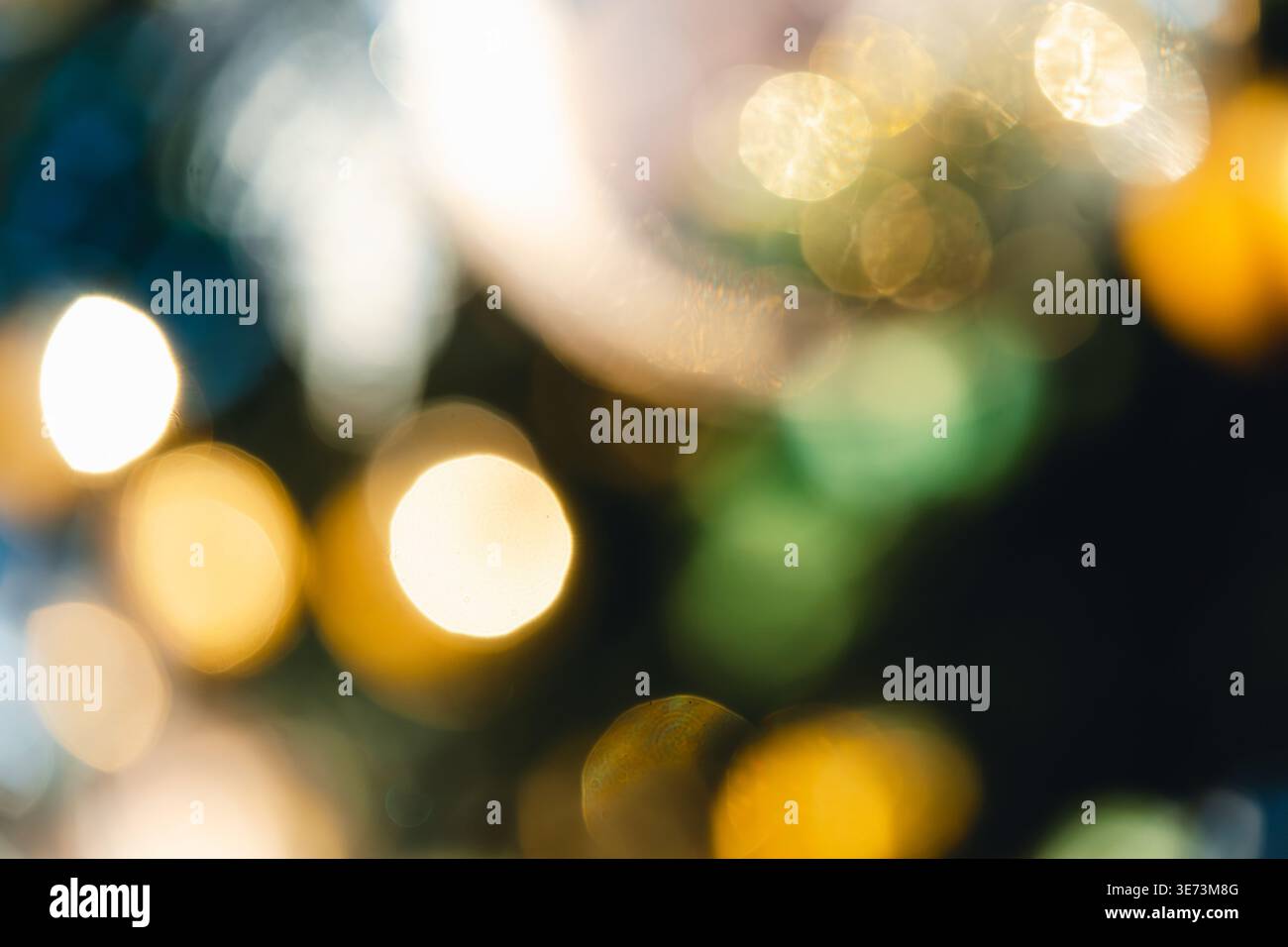 Luci dorate soffuse e fuori fuoco creano un'atmosfera festosa in questa vista astratta delle luci della città. L'effetto bokeh cattura il bagliore magico della h Foto Stock