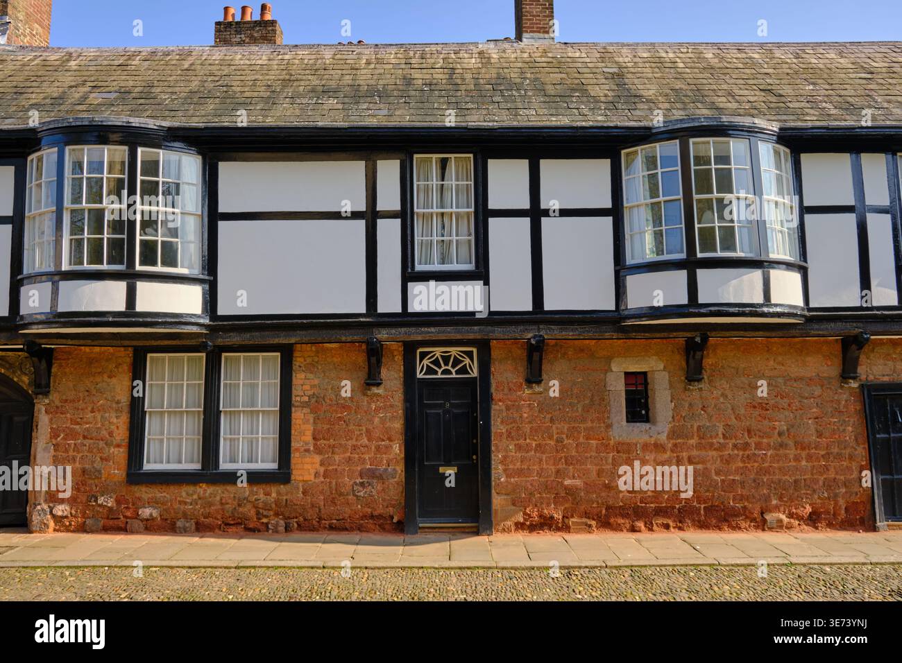 Exeter, Regno Unito - 22 marzo 2026. Un edificio in legno bianco e nero di stile Tudor con finestre a bovindo a strapiombo e arenaria rossa Foto Stock