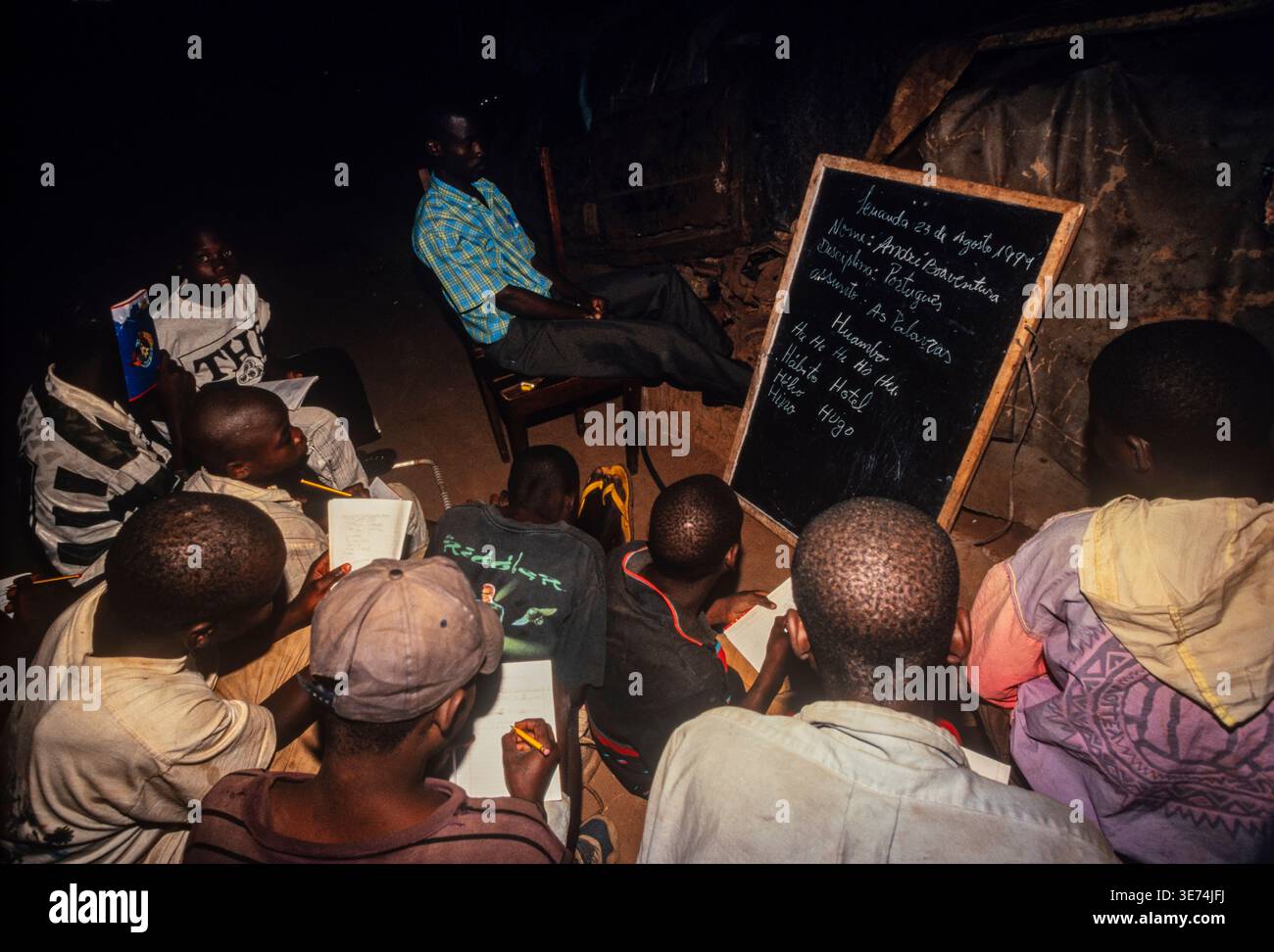 Casa i bambini di strada, vivendo in oggetto di dumping automobili, assistere a una notte mobile scuola gestita da un locale di carità, Luanda, Angola Foto Stock