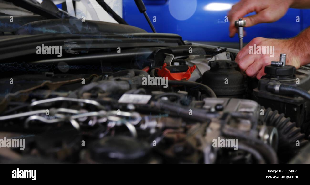 Serrare le mani del meccanico in manicotti corti girando una chiave a bussola nel vano motore, con morsetto rosso. Auto, primo piano, tecnico, officina, grasso, tubi flessibili Foto Stock