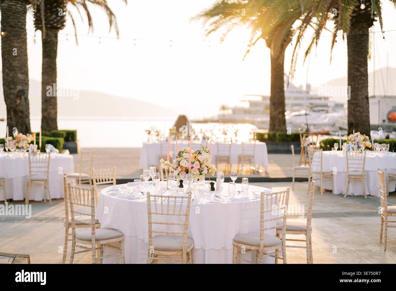 Festa del tramonto sulla spiaggia. Elegante festa sul lungomare con vista sul tramonto e arredi raffinati Foto Stock