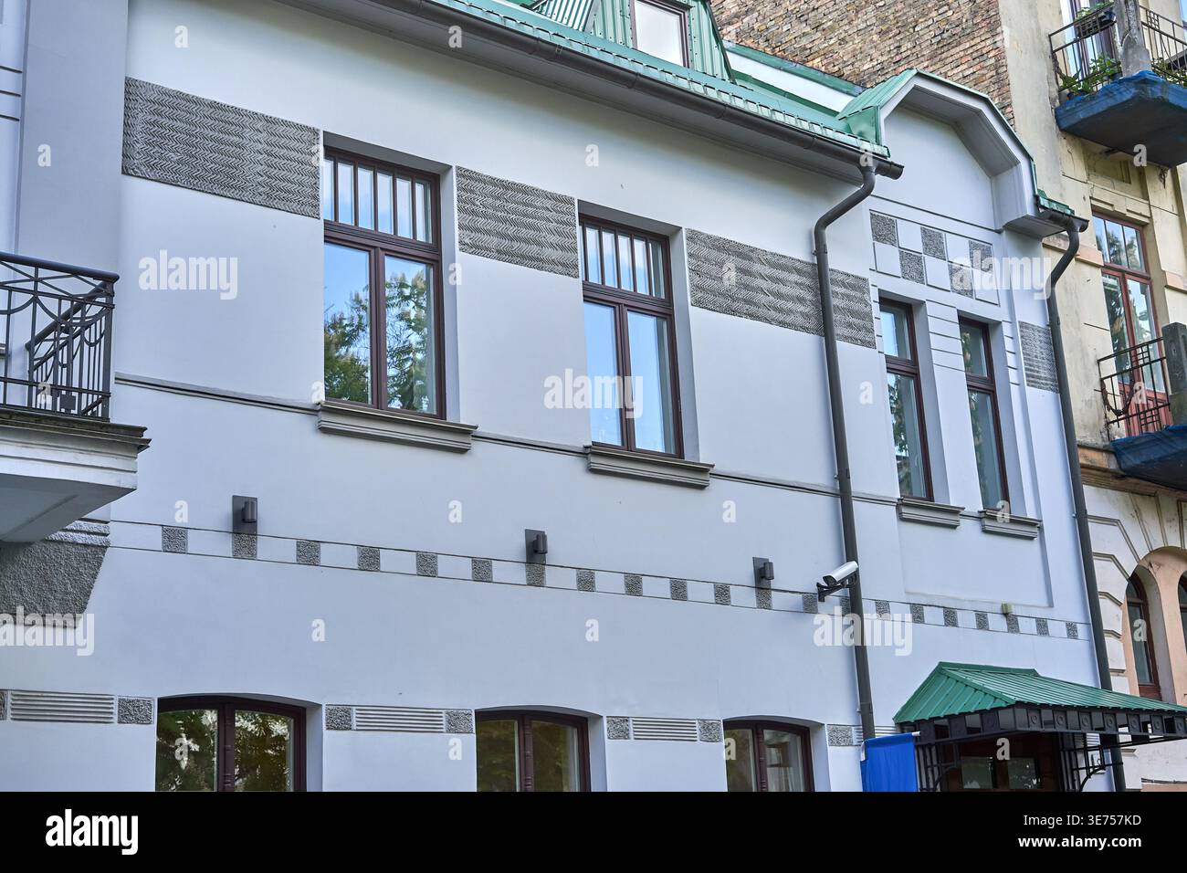L'immagine mostra la facciata di un edificio residenziale urbano rinnovato con un esterno bianco o grigio chiaro e una texture grigia decorativa Foto Stock