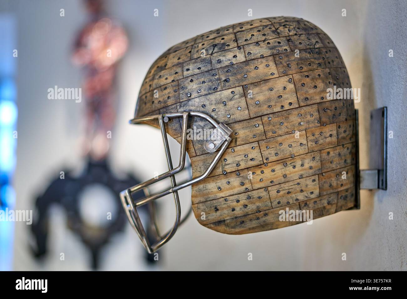 Primo piano di una scultura artistica di casco da football americano montata su un muro bianco. Il casco è costruito con doghe o piastrelle di legno stagionato Foto Stock
