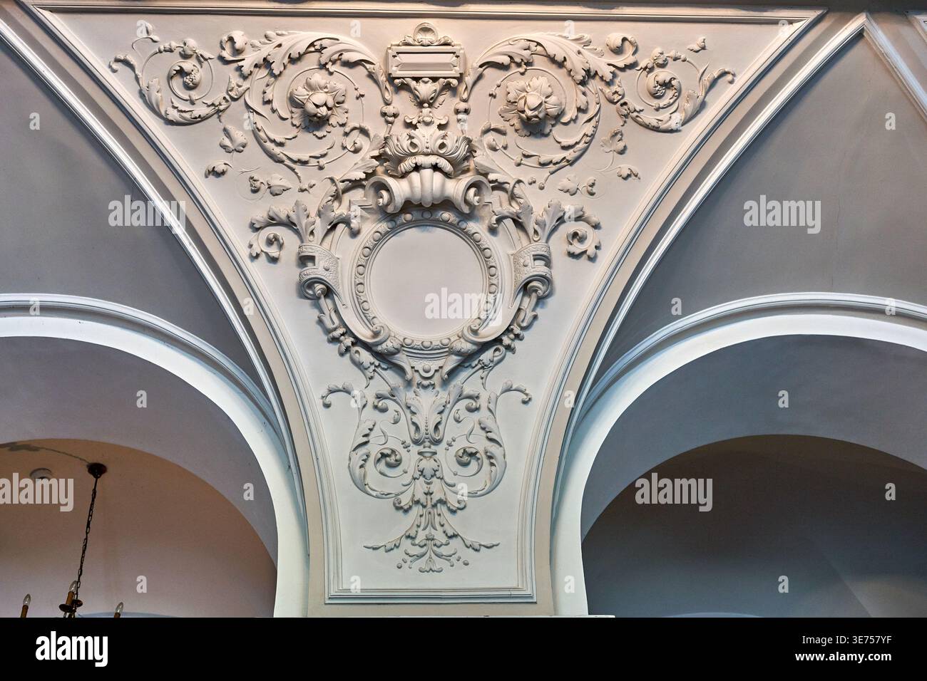 Vista ravvicinata di stucchi ornamentali sul soffitto in un interno storico, con elaborate decorazioni in stucco barocche o rococò all'interno di un triangolo Foto Stock