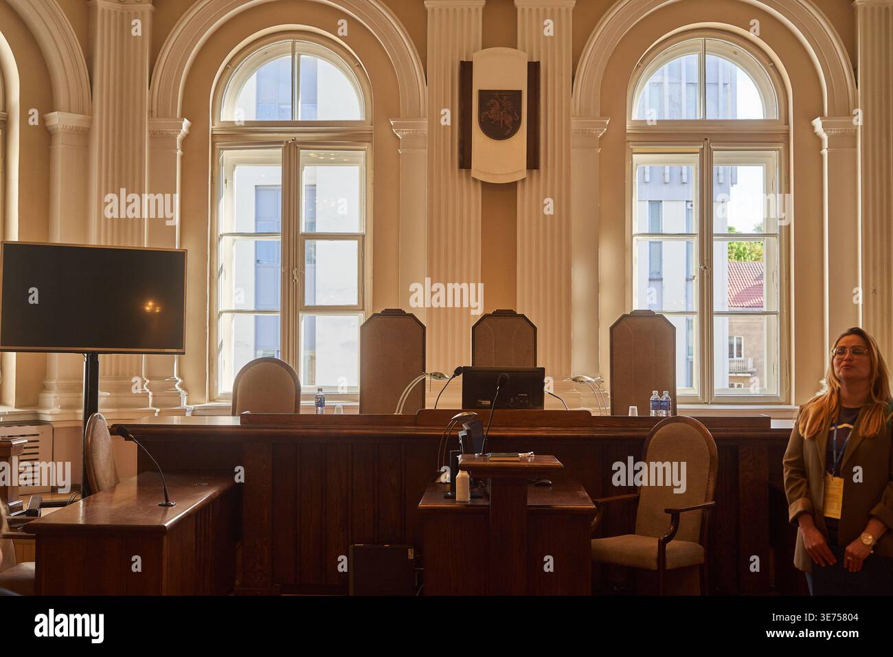 Interno di un'aula di tribunale o di una camera parlamentare formale con architettura classica, alte finestre ad arco, colonne ornate e legno Foto Stock