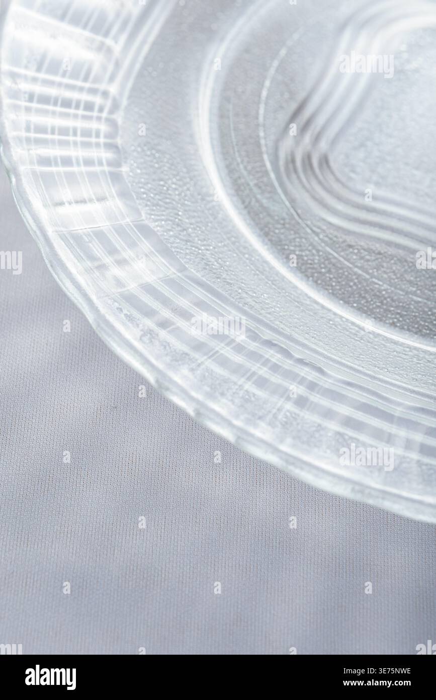 La vista ravvicinata mostra un'intricata lastra di vetro. Le luci soffuse da studio mettono in risalto le texture, creando un aspetto arioso e minimalista. Sfondo grigio tenue. Cibo e drin Foto Stock