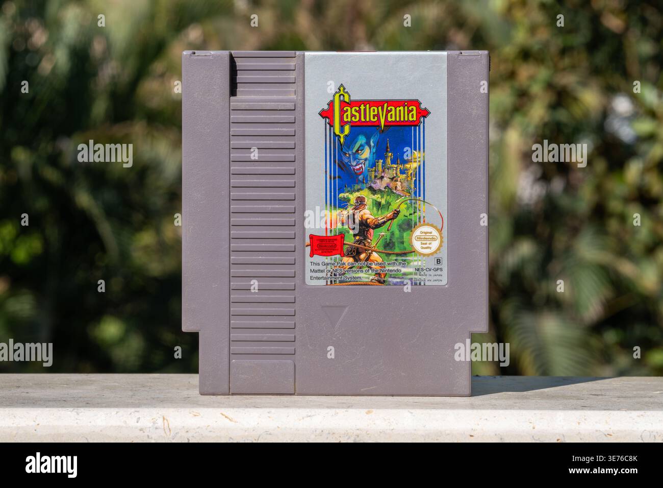Cartuccia originale PAL Nintendo NES Castlevania di Konami, plastica grigia con etichetta illustrata, appoggiata su una superficie in marmo con fogliame tropicale b Foto Stock