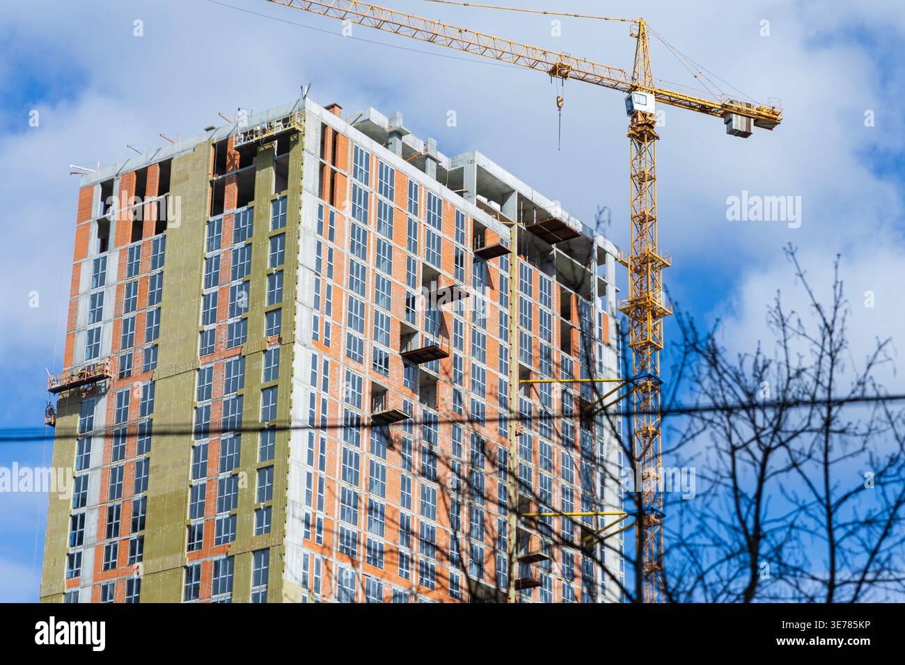 Costruzione di un moderno ed alto edificio di appartamenti con una gru gialla Foto Stock