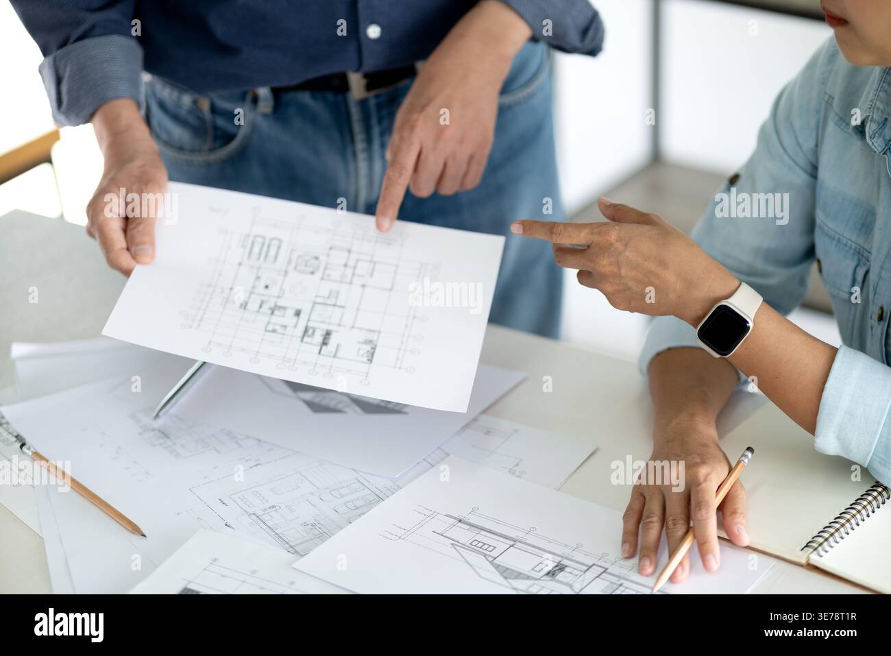 Architetto o ingegnere sta esaminando e verificando i dettagli del progetto dell'edificio per verificare se soddisfa gli obiettivi di pianificazione dell'amministratore Foto Stock