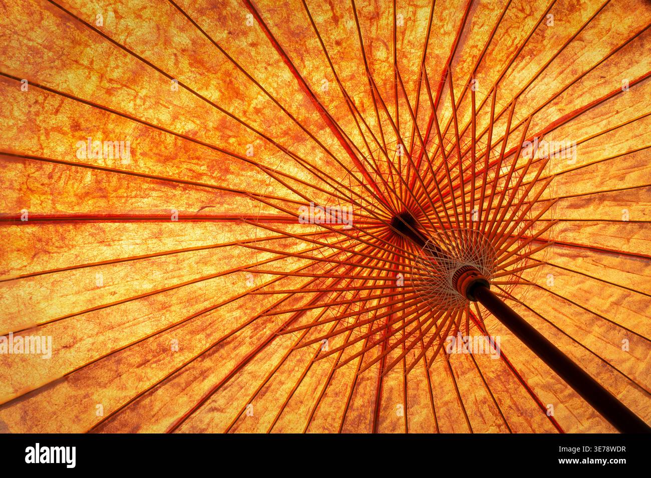 Primo piano di un ombrellone asiatico arancione, vista dal basso, vibrante sfondo asiatico Foto Stock
