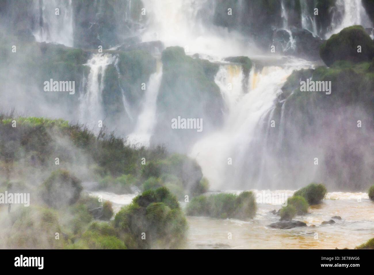 Le cascate multiple del sistema delle cascate dell'Iguazu versano su incroci rocciosi ricoperti di muschio, riempiendo l'aria con una fitta nebbia e spruzzi a Foz do Iguacu, Pa Foto Stock