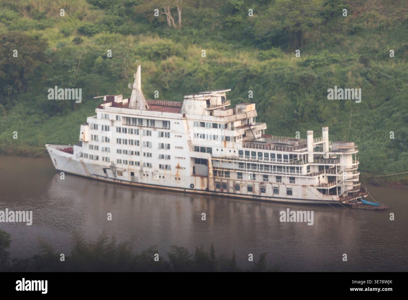Una grande nave da crociera, pesantemente arrugginita e in deterioramento, è abbandonata lungo le rive del fiume Paraná vicino a Foz do Iguazú, in Brasile. Il multi-deck ve Foto Stock