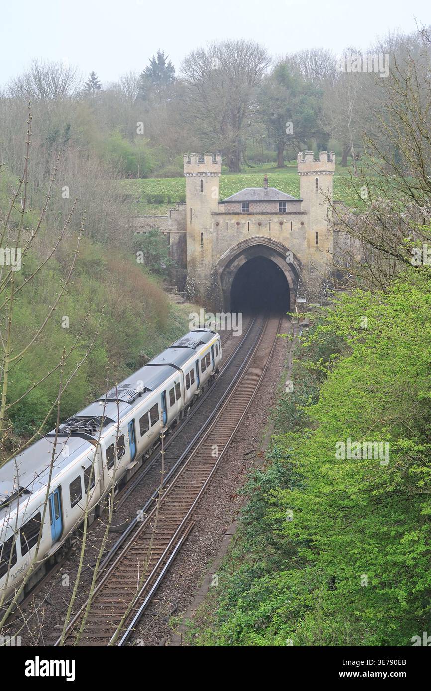 Un treno Thameslink entra nel tunnel ferroviario di Clayton sulla linea Londra-Brighton del Regno Unito. Il portale è famoso per il suo stile castello e il cottage. Foto Stock