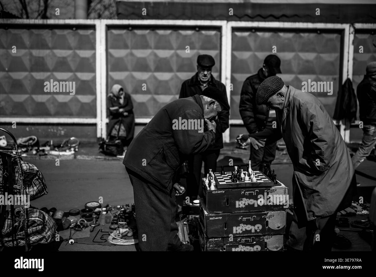Darnytsia, Kiev, Ucraina – 21 marzo 2014: Uomini anziani profondamente coinvolti in una partita strategica di scacchi in un vivace mercato di strada, circondati da un osservatore Foto Stock