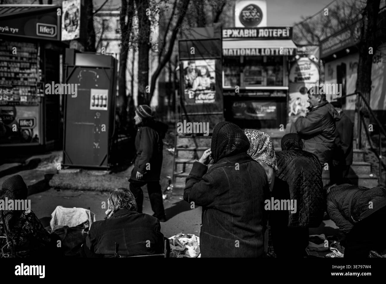 Darnytsia, Kiev, Ucraina – 21 marzo 2014: Un sincero colpo in bianco e nero di varie persone, molte con coperture della testa, riunite o sedute su un vivace cit Foto Stock