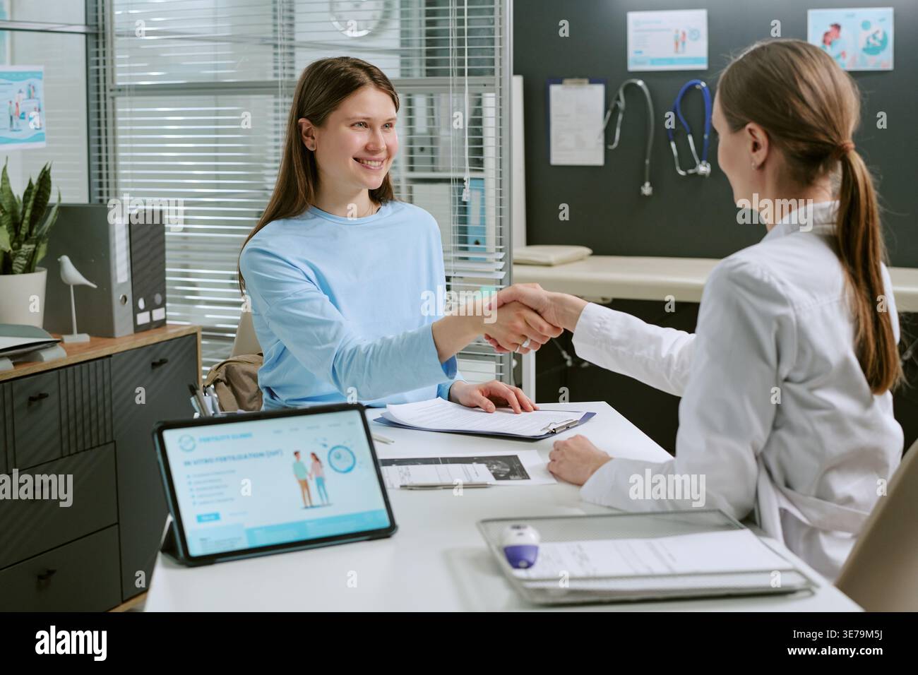 Donna adulta paziente che stringe la mano al medico durante la consultazione Foto Stock