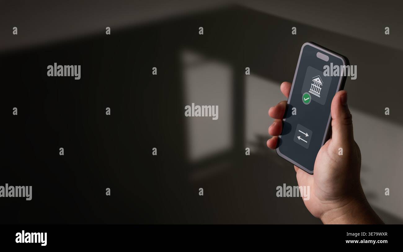 Primo piano di una persona con uno smartphone che visualizza un'app di mobile banking con icone di trasferimento e conferma in un'impostazione minima scura con copia spa Foto Stock