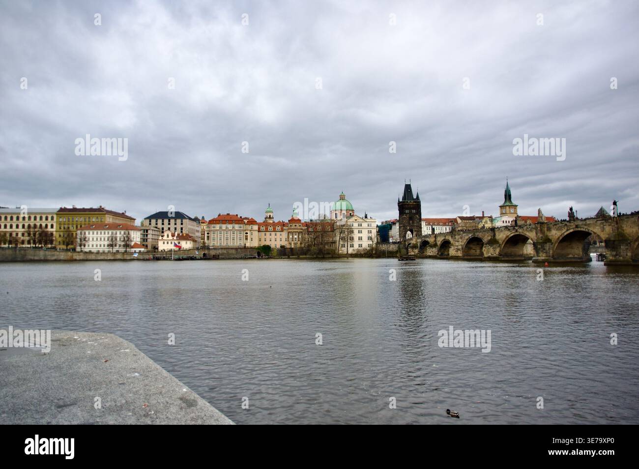 Lo storico skyline di Praga presenta l'iconico Ponte Carlo che attraversa il fiume Moldava, gli edifici della città vecchia con cupole e torri che si riflettono in un ambiente tranquillo Foto Stock