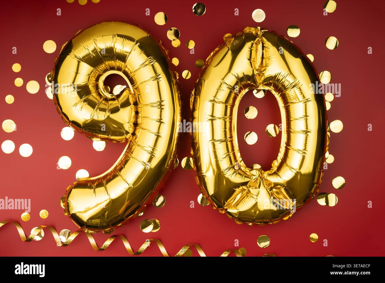 Buon compleanno congratulazioni. 90 anni. Palloncini dorati numero 90 su sfondo rosso con coriandoli, novant'anni. Foto Stock