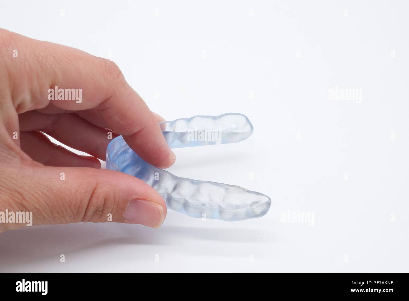 Mano che tiene in mano una protezione dentaria trasparente per proteggere i denti dalla molatura Foto Stock
