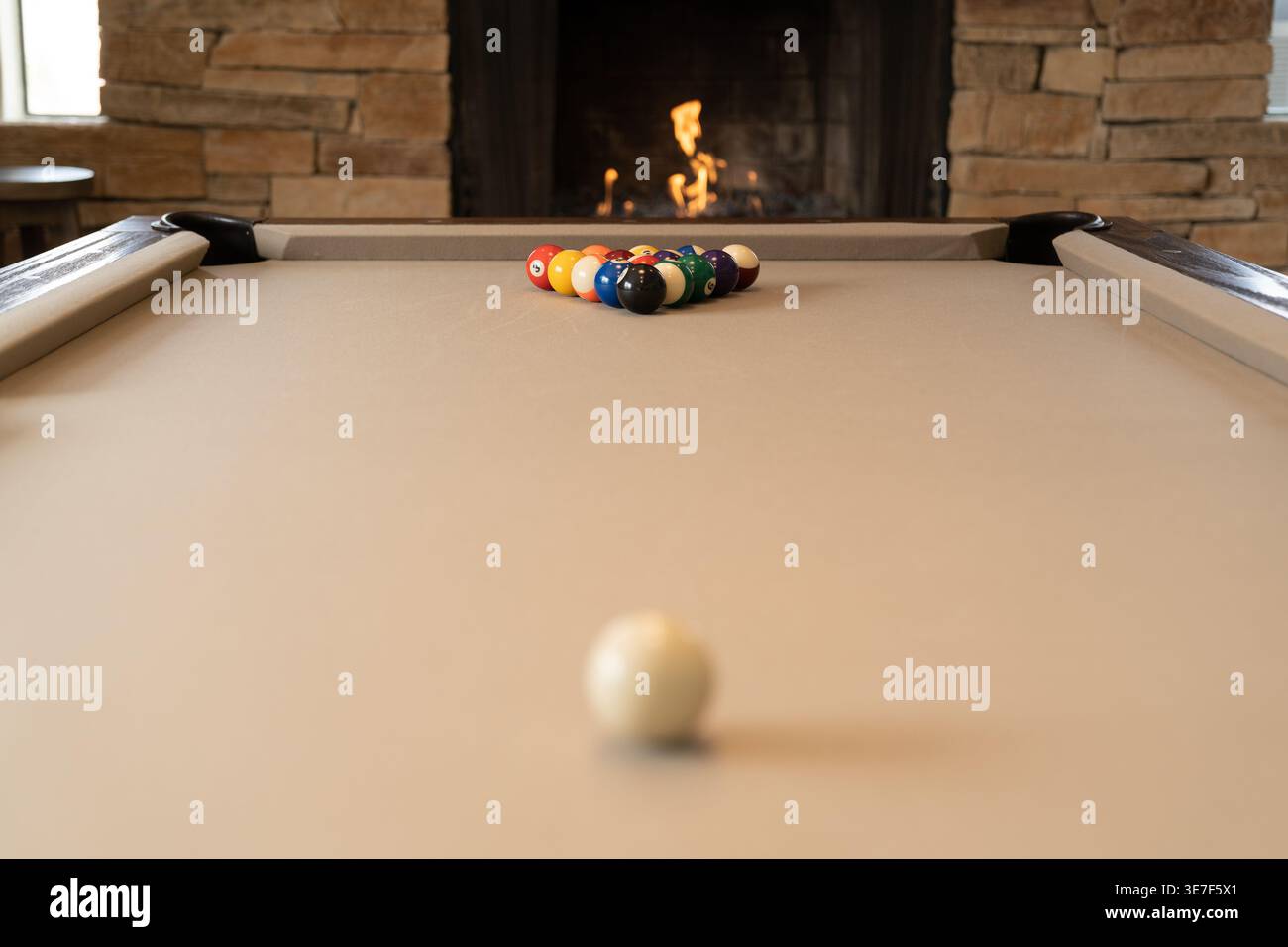 Primo piano di un tavolo da biliardo con palline, palline e camino che bruciano sullo sfondo Foto Stock