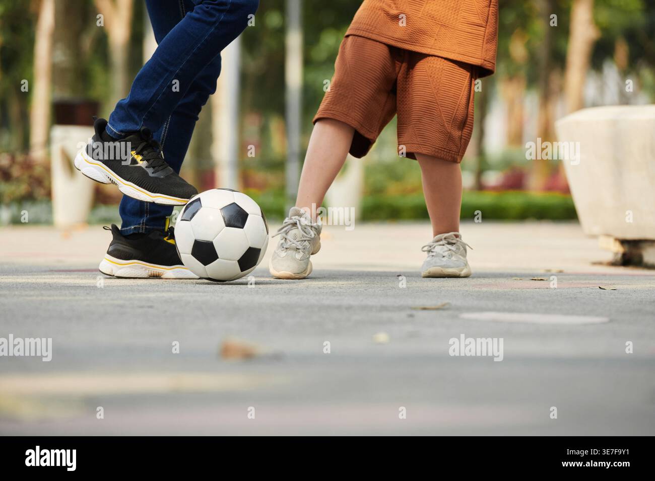 Primo piano del padre asiatico che gioca a calcio con il figlio nel parco Foto Stock