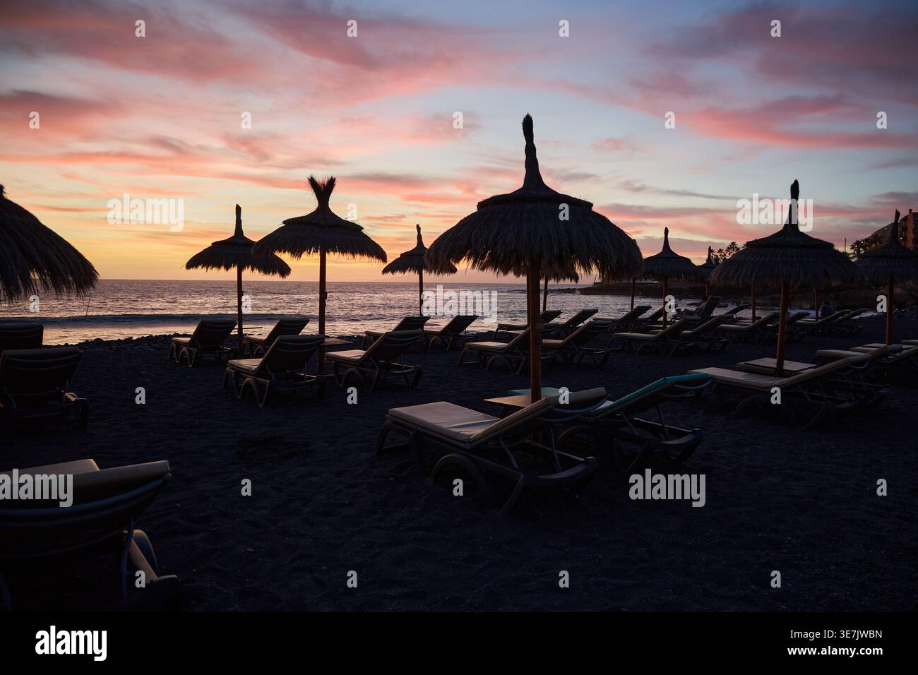 Sunset Beach con lettini e ombrelloni di paglia Foto Stock