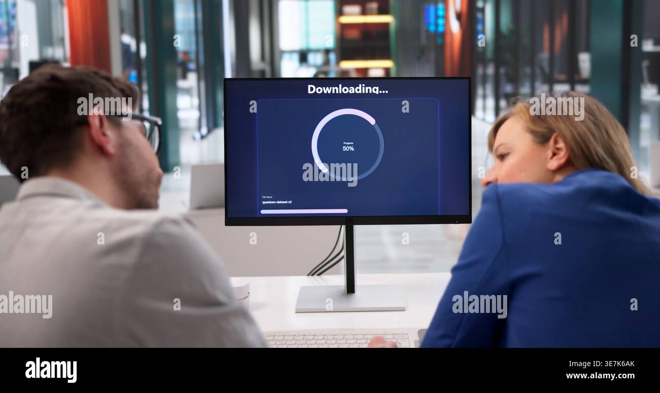 Dipendenti che passano del tempo in attesa del completamento del trasferimento di file sul posto di lavoro Foto Stock