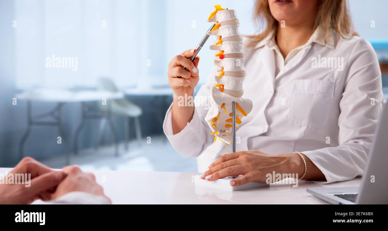 Il giovane paziente maschio riceve una consulenza approfondita per la cura della colonna vertebrale dal chiropratico Foto Stock