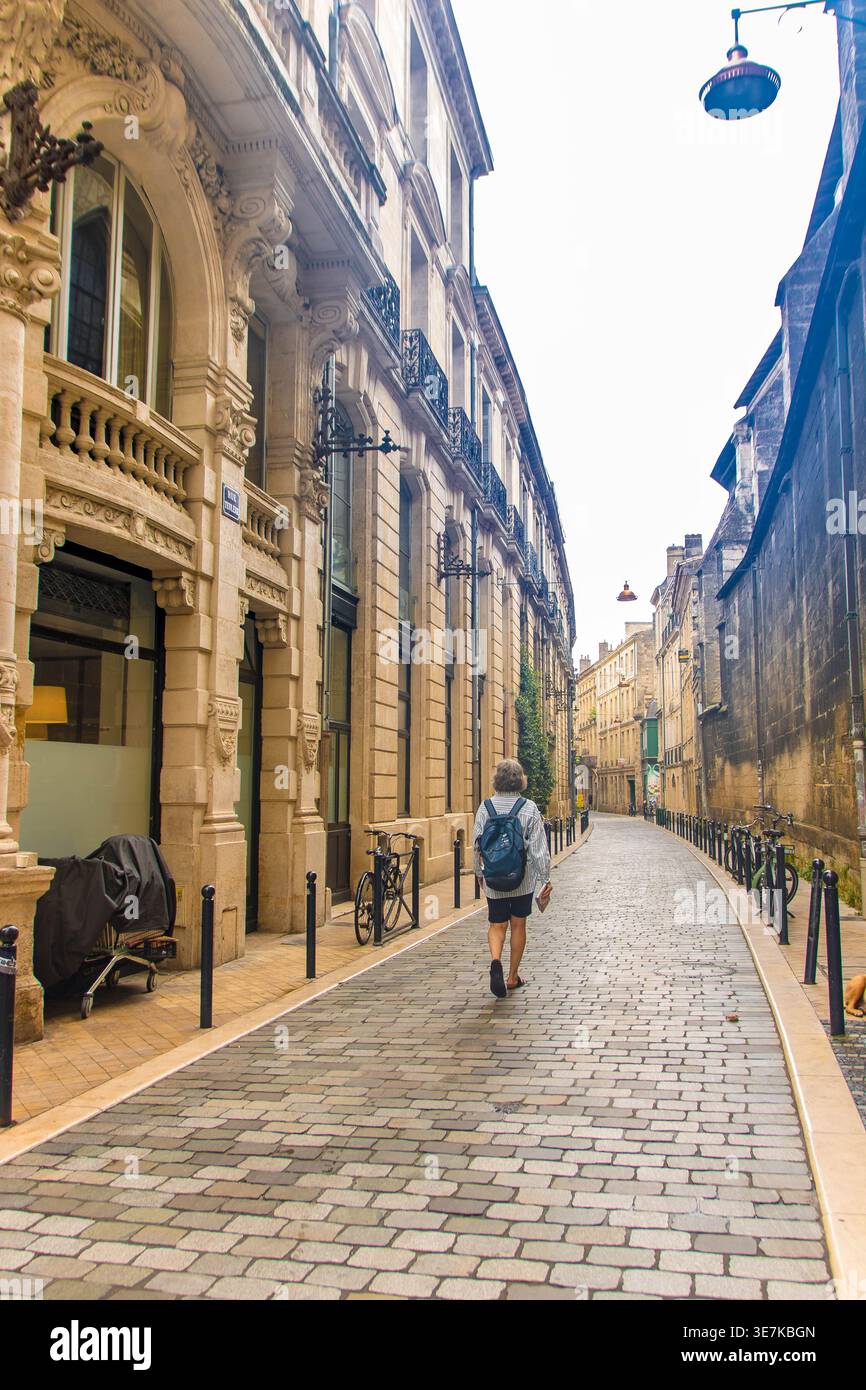 A Bordeaux, Francia, il 08.30.25, il turista cammina lungo Rue Teulère, una tradizionale strada acciottolata con architettura storica Foto Stock