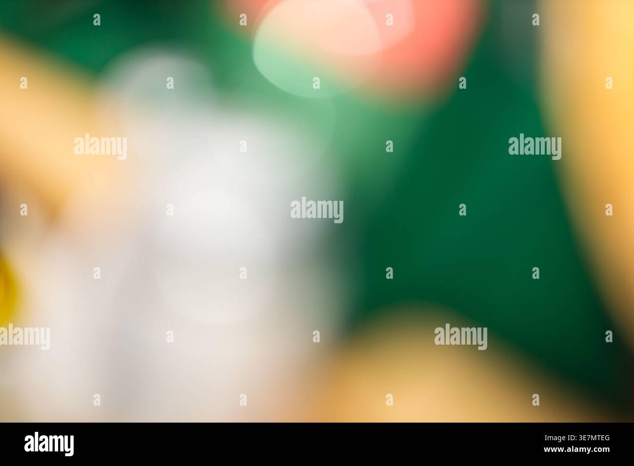 Sfondo bokeh astratto con forme chiare di verde bianco e rosso sfocate su verde scuro Foto Stock